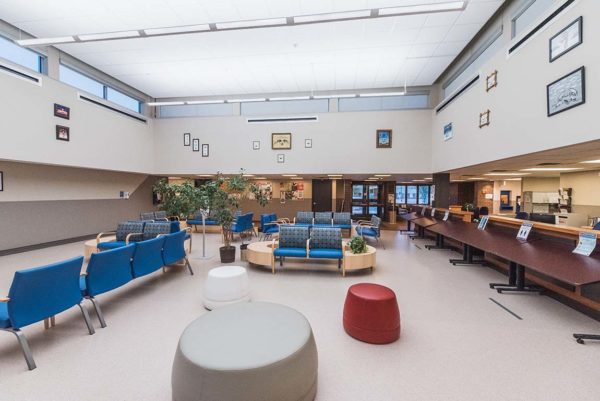 A well-lit clinic waiting room filled with padded blue chairs.