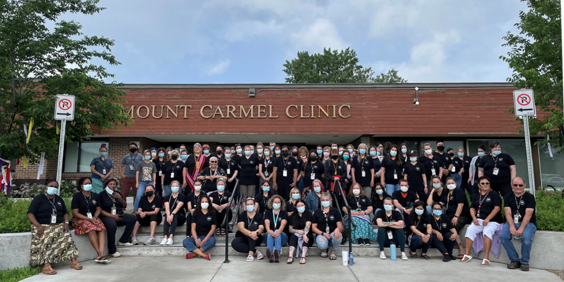 Mount Carmel Clinic staff pose on building front steps wearing face masks